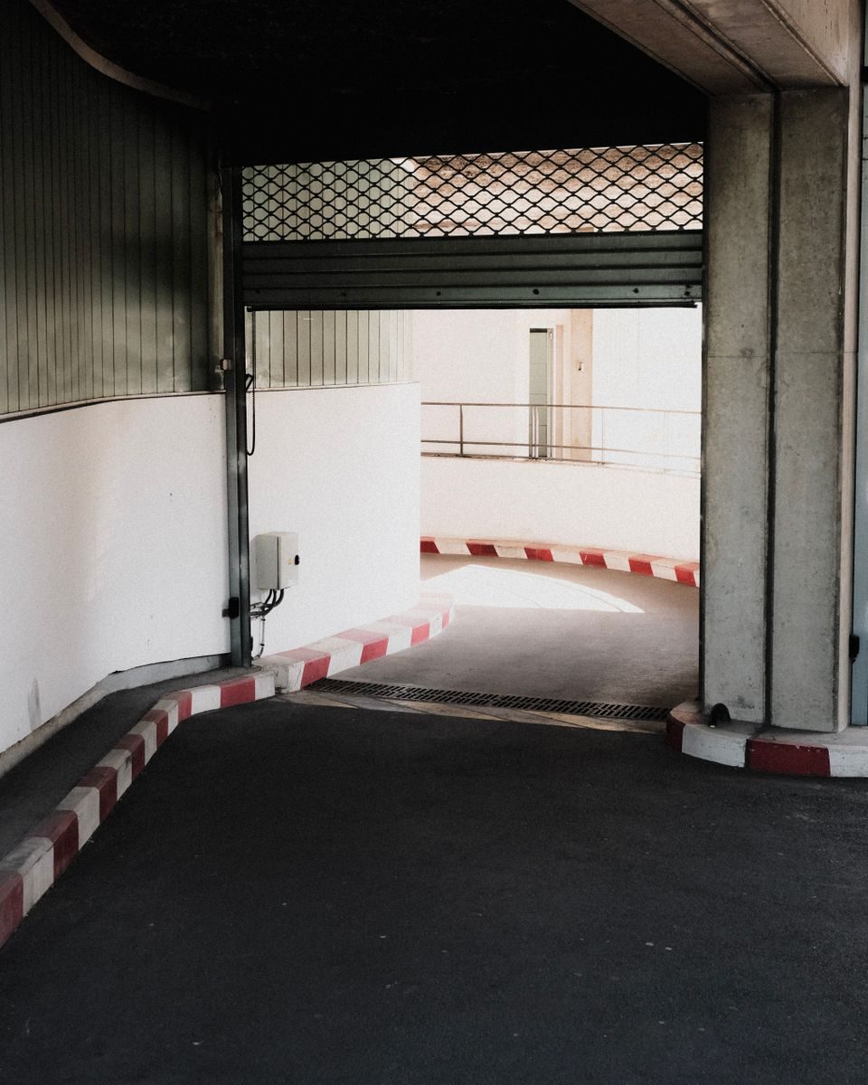 Entrance of an underground parking lot with roller shutter and concrete walls.
