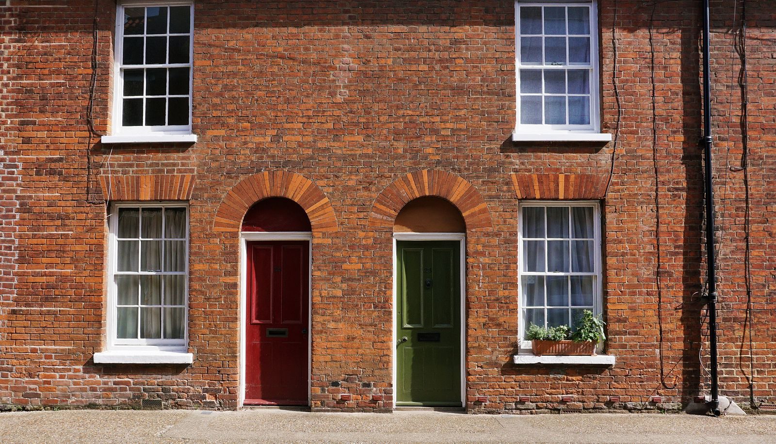 A vintage brick facade featuring red and green doors in an urban setting.