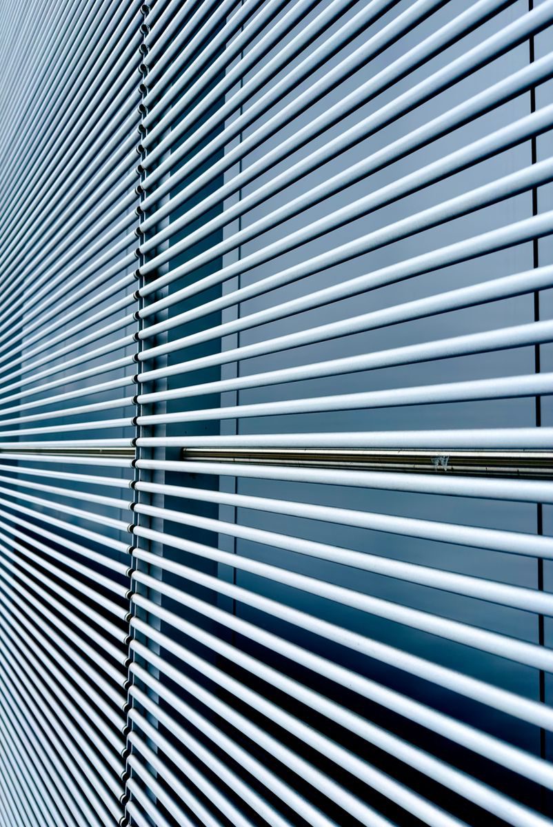 Abstract image of modern window blinds with straight horizontal lines and cool tones.
