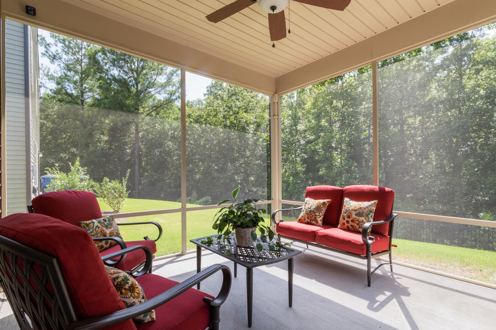 Bright modern patio featuring red cushioned seating and a lush green garden view.